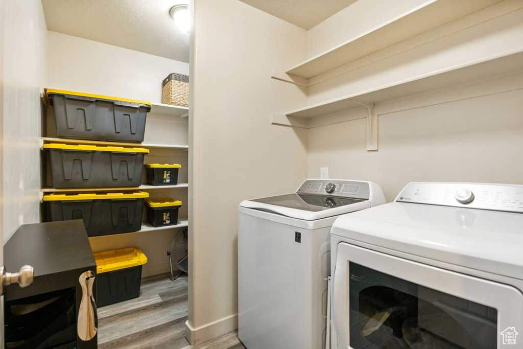 Washroom with washer and dryer and wood finished floors