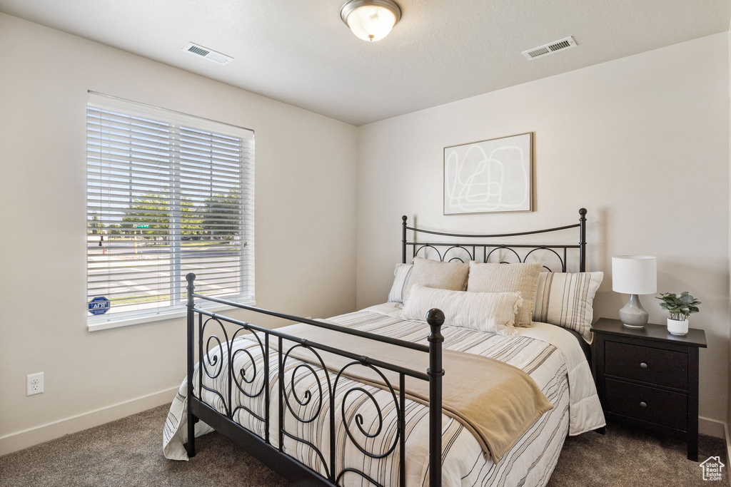 Carpeted bedroom featuring multiple windows and baseboards