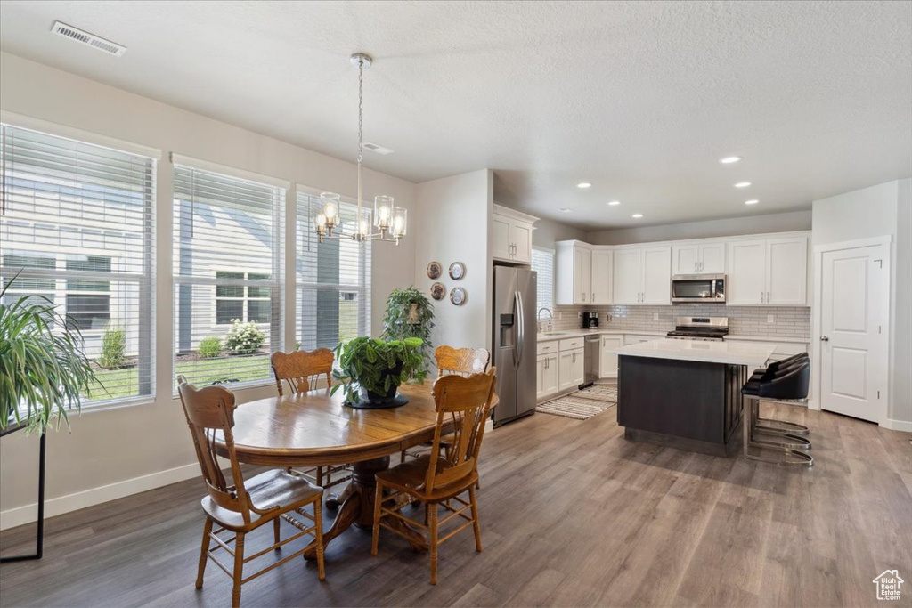 Dining area with a chandelier, light wood-type flooring, baseboards, and recessed lighting