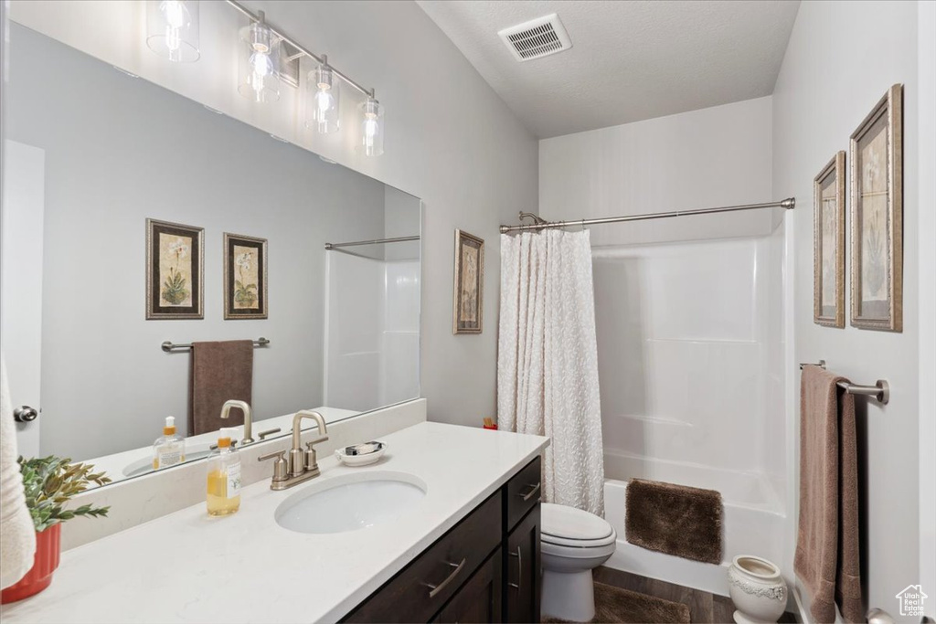 Full bathroom featuring toilet, vanity, shower / bath combo, and wood finished floors