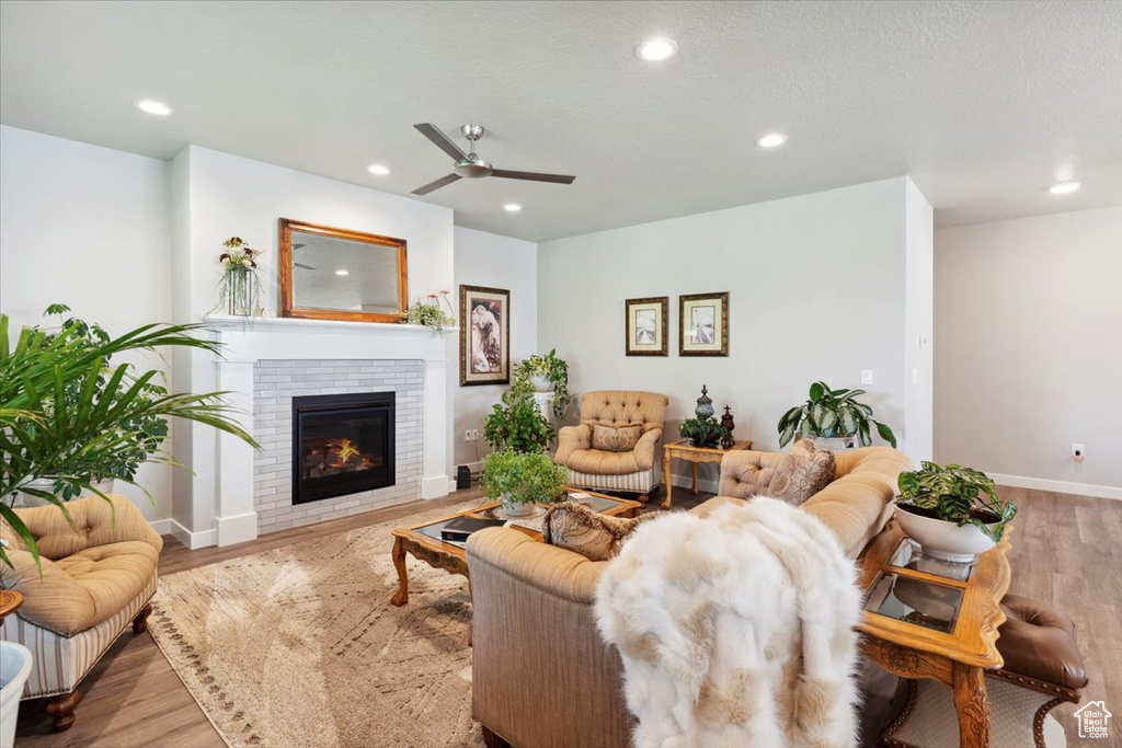 Living room with ceiling fan, wood finished floors, recessed lighting, a fireplace, and baseboards