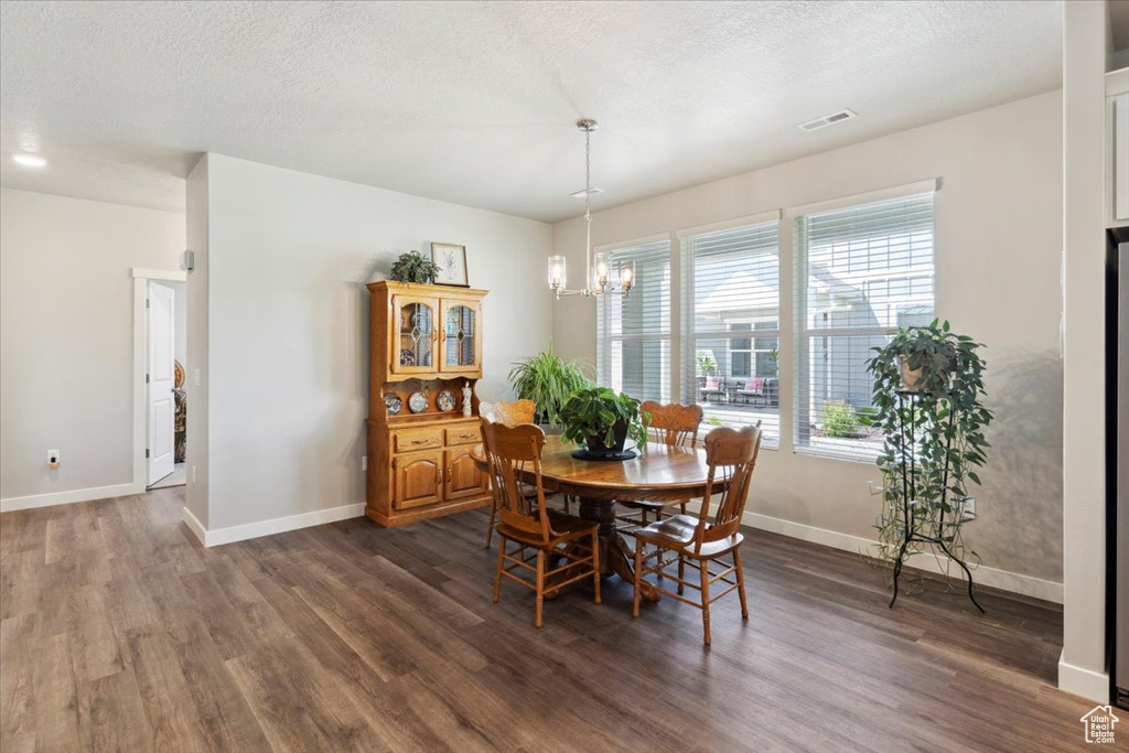 Dining space with dark wood-style floors, a chandelier, baseboards, and a textured ceiling