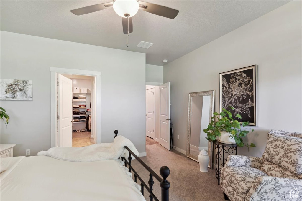 Bedroom with light carpet, baseboards, a spacious closet, and a ceiling fan