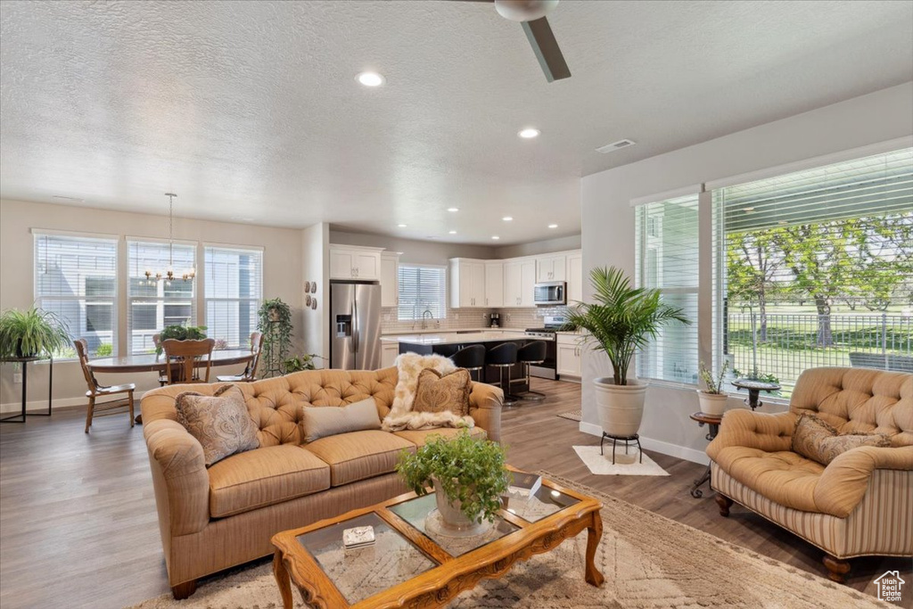 Living room featuring light wood-style flooring, baseboards, a textured ceiling, recessed lighting, and a ceiling fan