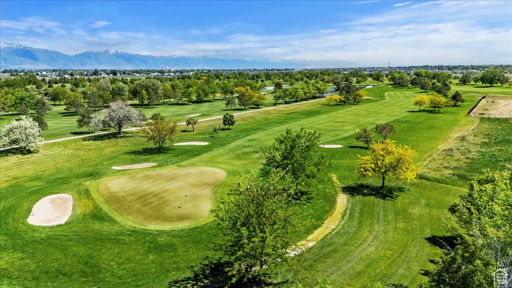 Drone / aerial view of a mountainous background, a golf course, and a tree filled landscape
