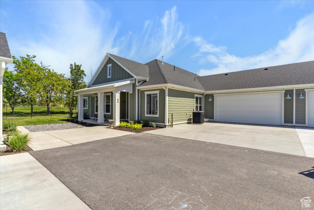 View of front of home with concrete driveway, board and batten siding, a porch, an attached garage, and roof with shingles
