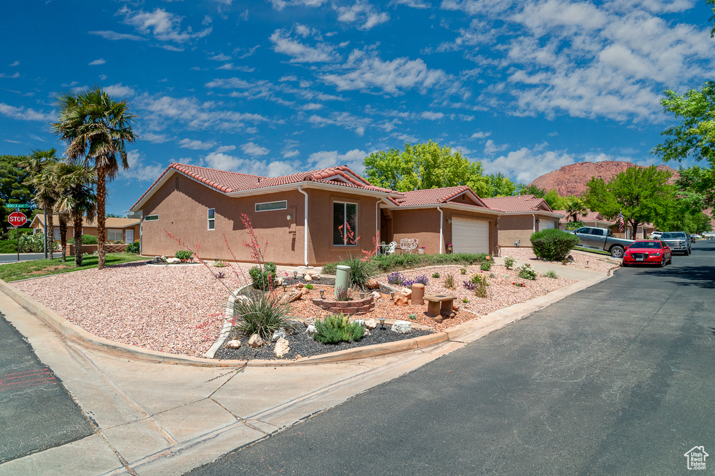 Single story home featuring a tile roof, a garage, and stucco siding