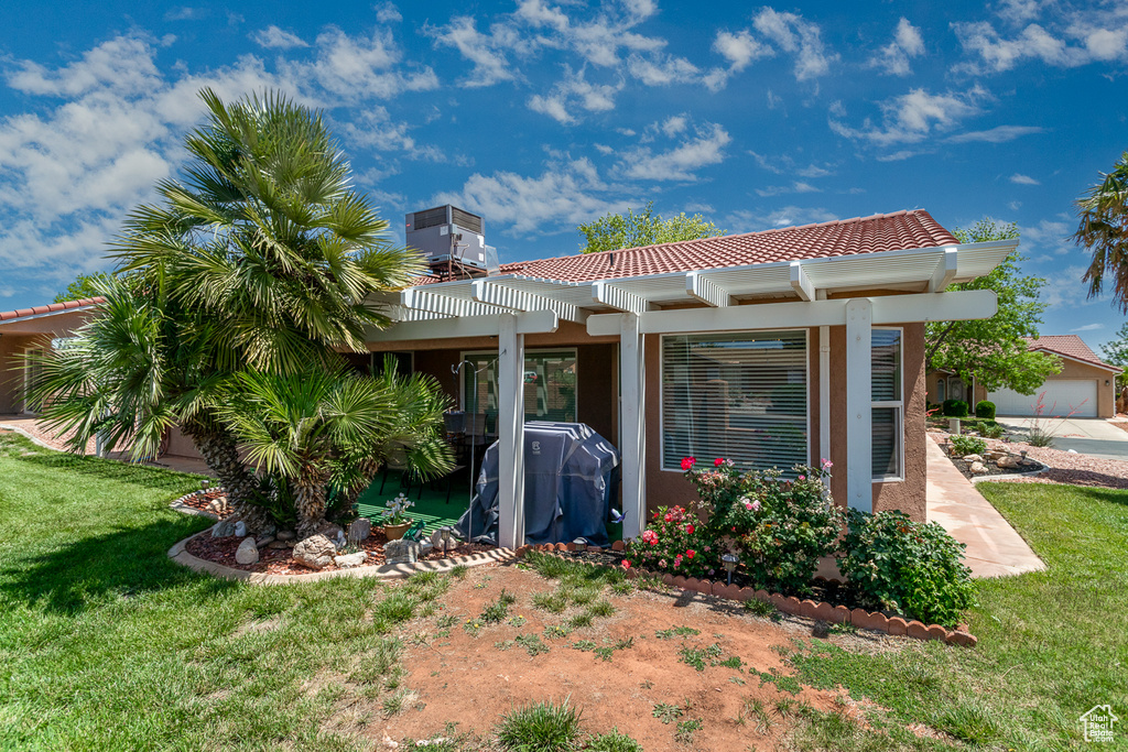 Back of property with a pergola, a yard, a tiled roof, and stucco siding