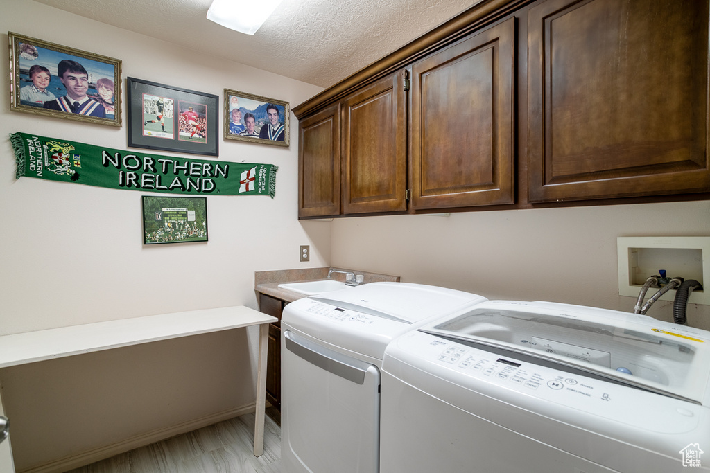 Laundry room with washing machine and dryer, cabinet space, and a textured ceiling