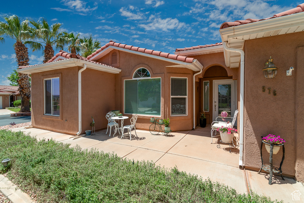 Rear view of property with stucco siding, a patio area, and a tile roof