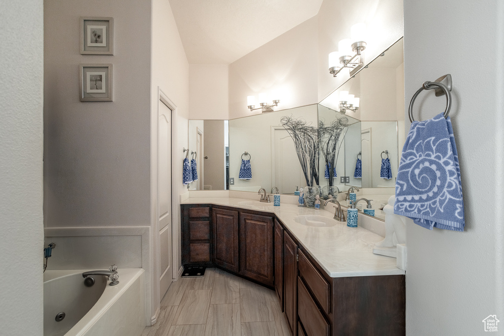 Bathroom with a bathtub, double vanity, and marble look tiles
