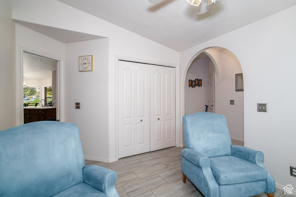 Sitting room featuring arched walkways, baseboards, lofted ceiling, and ceiling fan