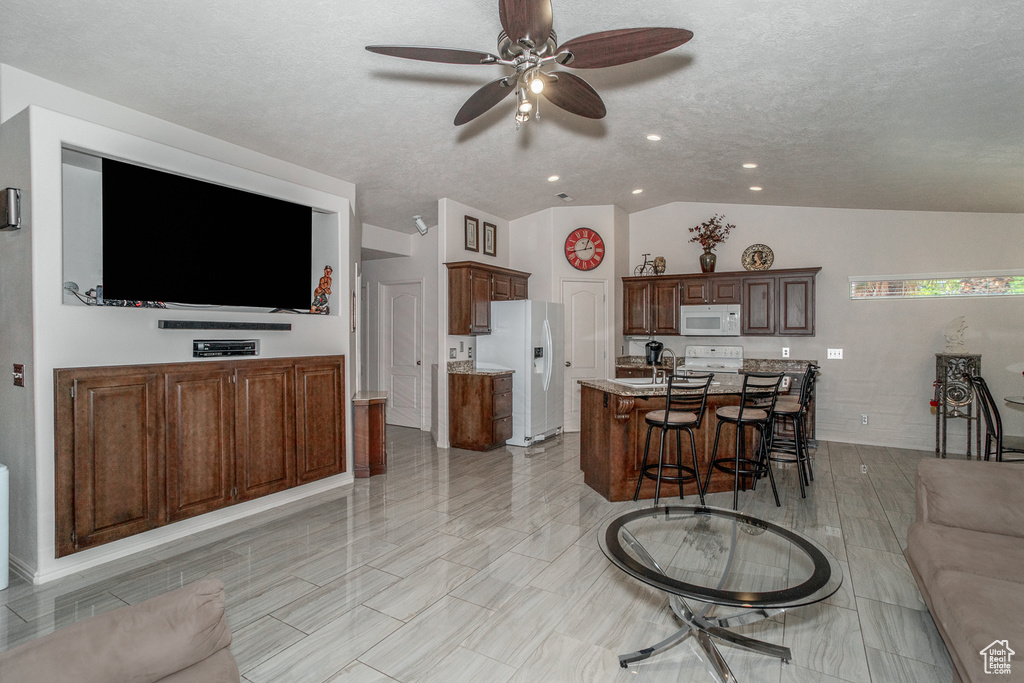 Living area featuring a ceiling fan, vaulted ceiling, recessed lighting, and a textured ceiling