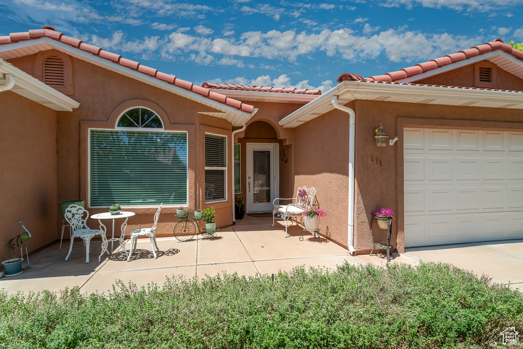 Property entrance featuring stucco siding, a tile roof, and a garage
