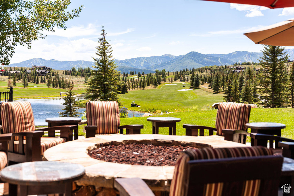 View of patio with a fire pit, view of golf course, and a water and mountain view