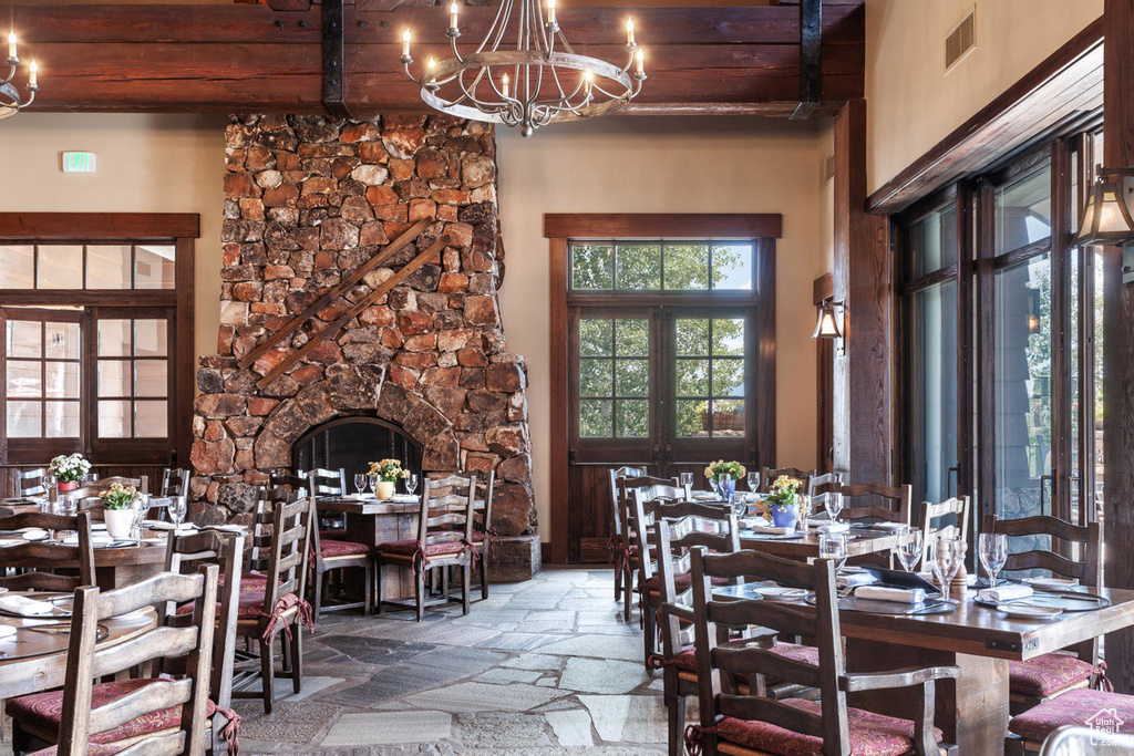 Dining room with a chandelier, stone tile flooring, and wooden ceiling with exposed beams