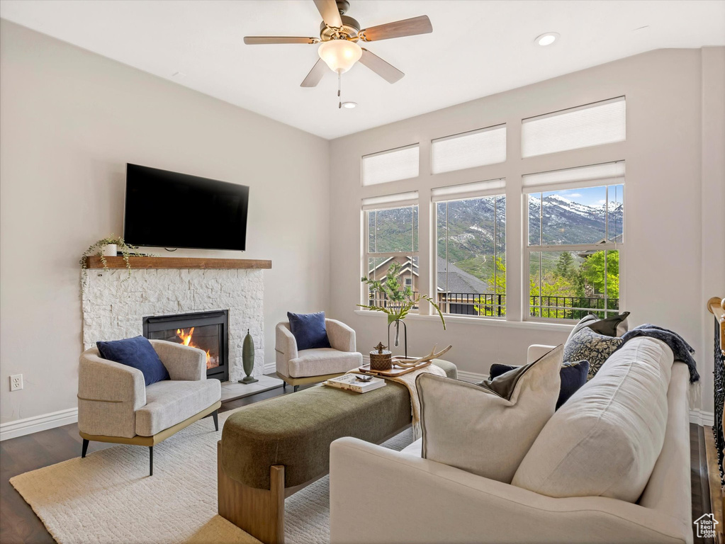 Living area with wood finished floors, healthy amount of natural light, a stone fireplace, baseboards, and recessed lighting