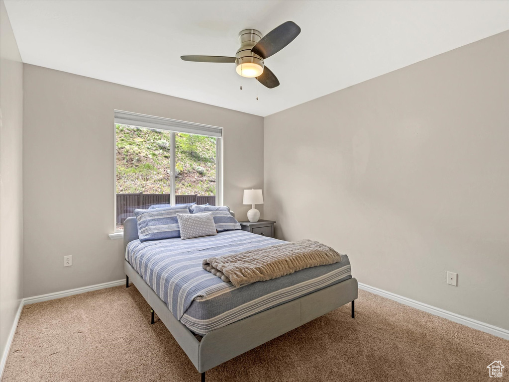Bedroom featuring light colored carpet, baseboards, and a ceiling fan