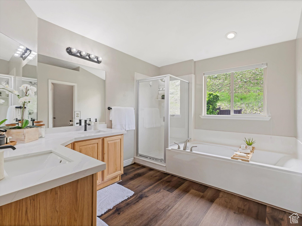 Bathroom with a shower stall, a bath, vanity, wood finished floors, and recessed lighting