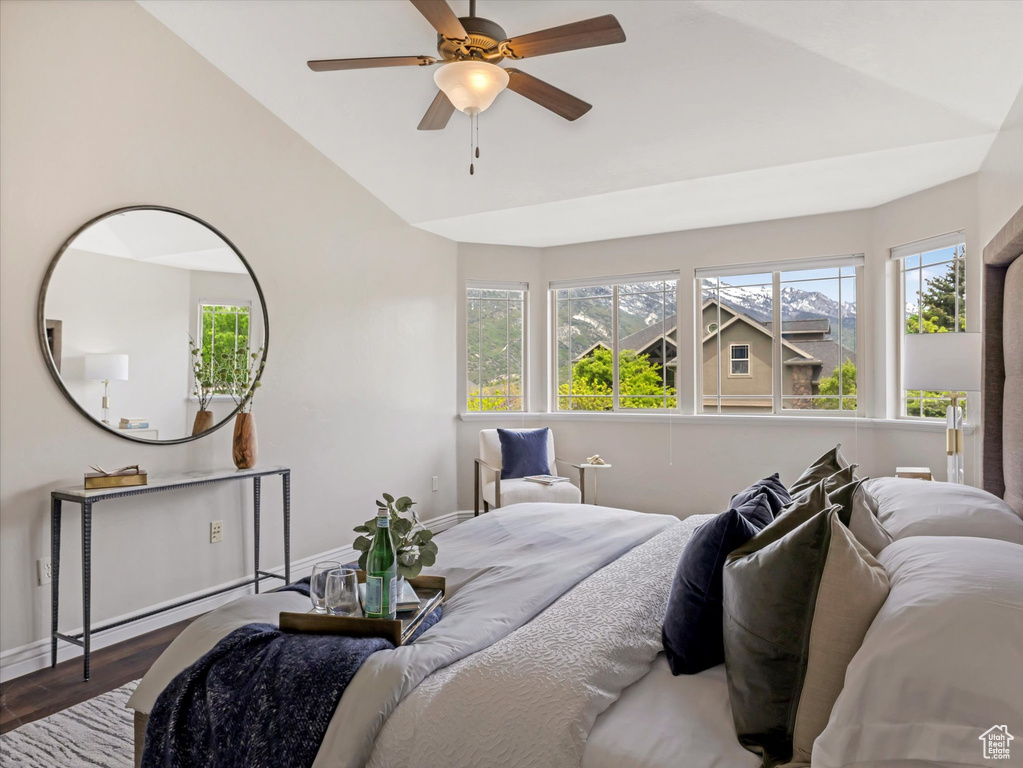 Bedroom with baseboards, wood finished floors, high vaulted ceiling, and a ceiling fan