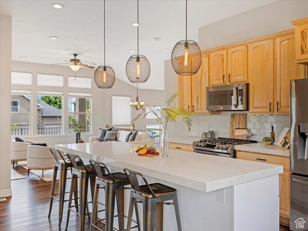Kitchen featuring stainless steel appliances, open floor plan, a ceiling fan, a kitchen island, and backsplash
