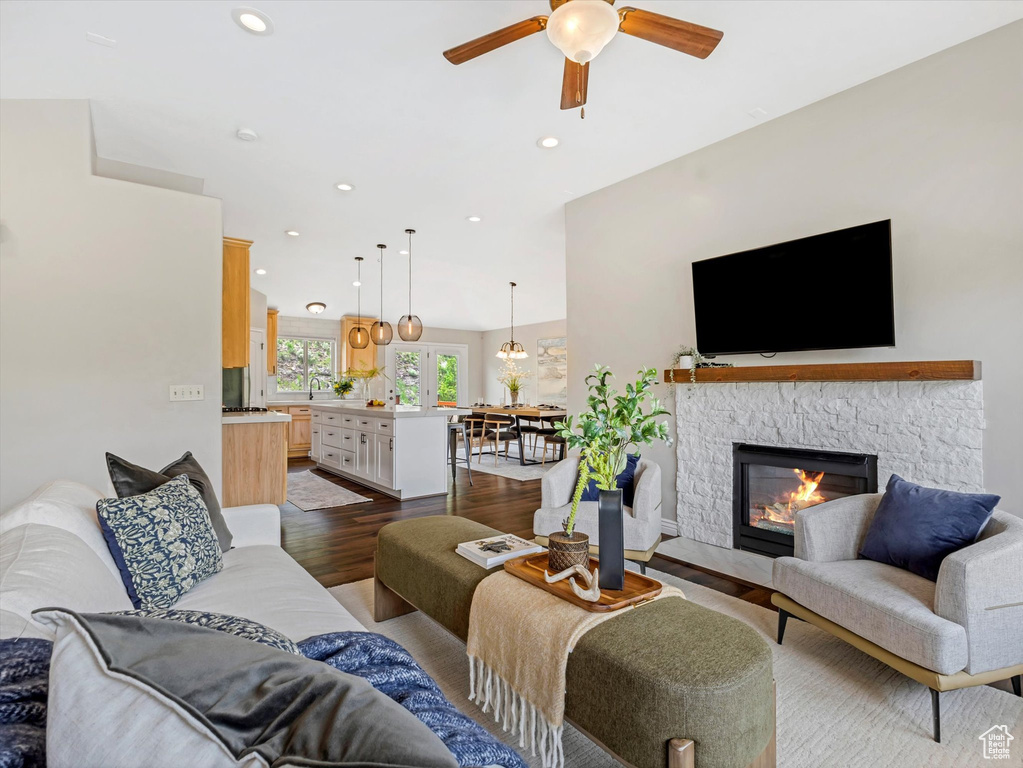 Living area featuring a ceiling fan, dark wood-type flooring, a stone fireplace, and recessed lighting