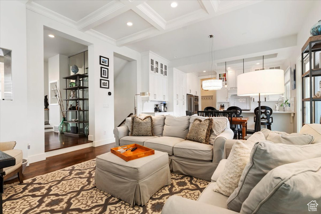 Living area featuring dark wood finished floors, beam ceiling, crown molding, baseboards, and coffered ceiling