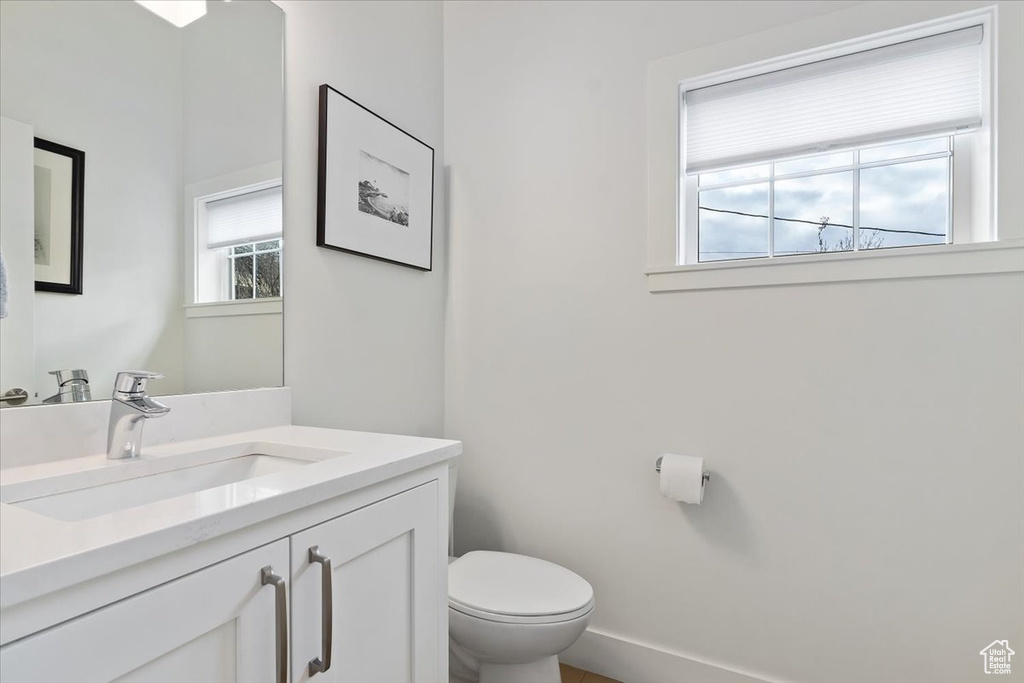 Half bathroom with plenty of natural light, toilet, and vanity