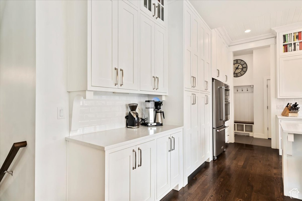 Kitchen with high end fridge, light countertops, backsplash, white cabinetry, and dark wood-style floors