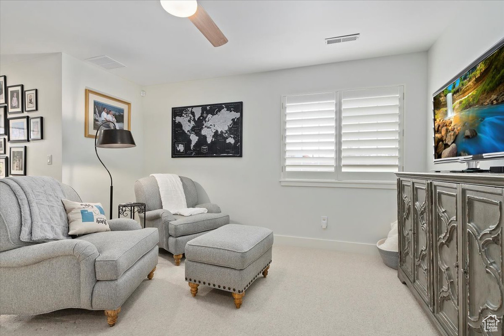Carpeted living area featuring ceiling fan and baseboards