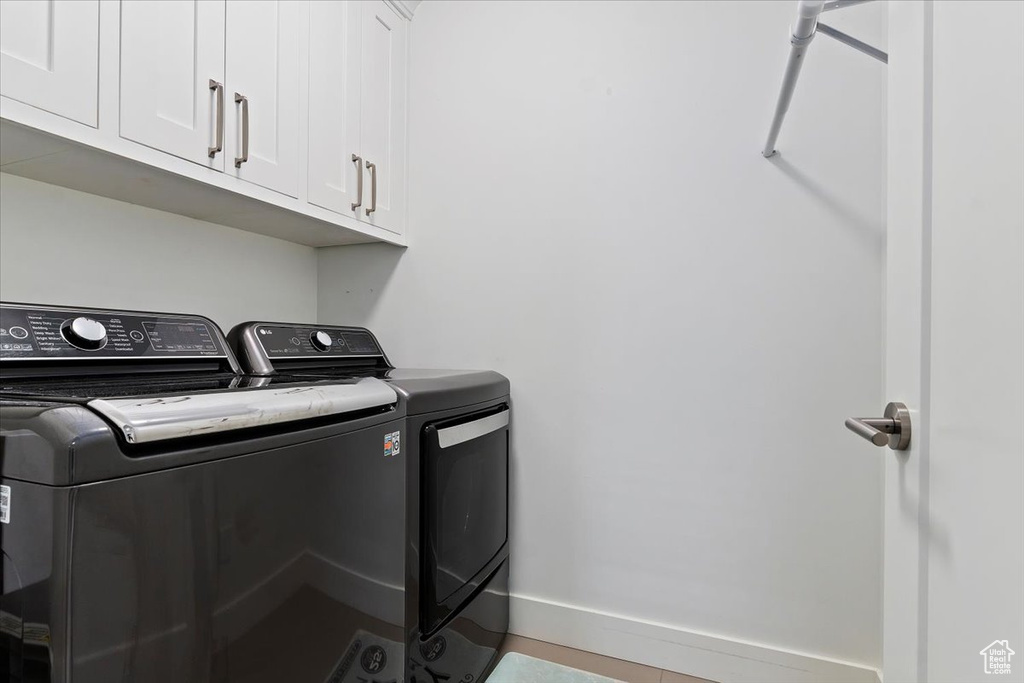 Washroom with washing machine and dryer, cabinet space, and baseboards