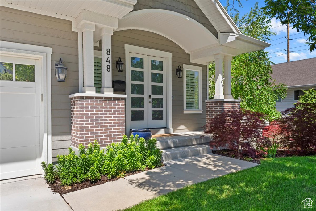 View of exterior entry featuring covered porch and brick siding