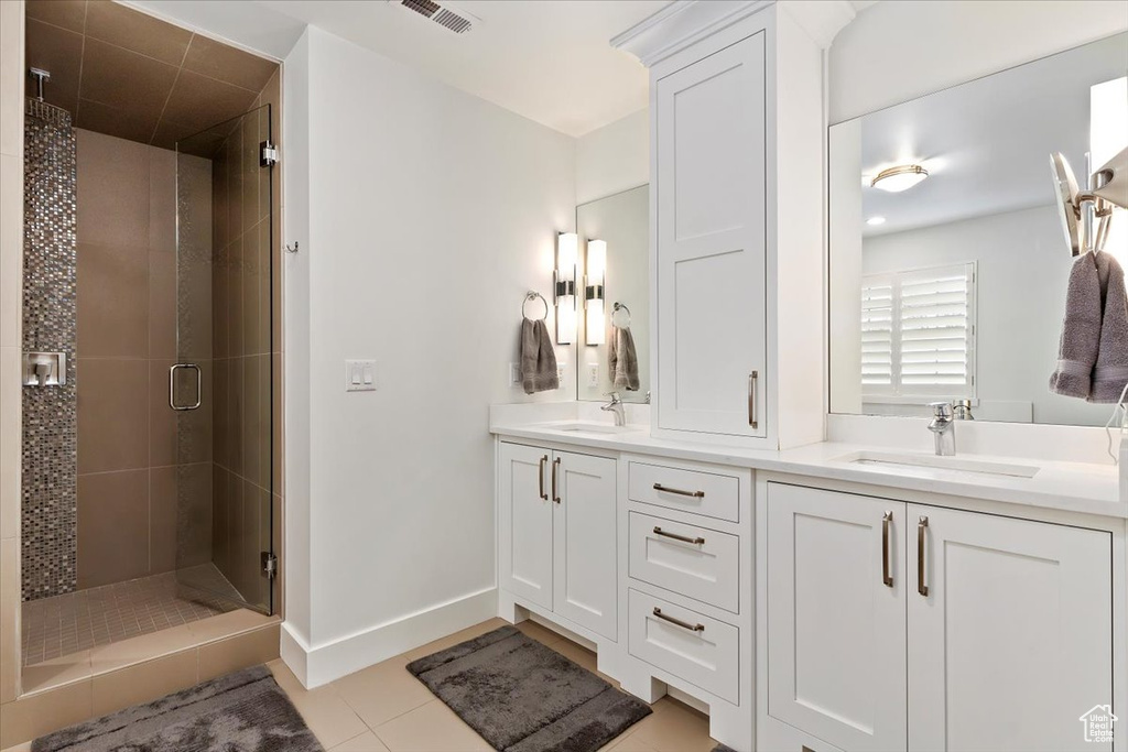 Full bathroom with a stall shower, double vanity, tile patterned flooring, and baseboards