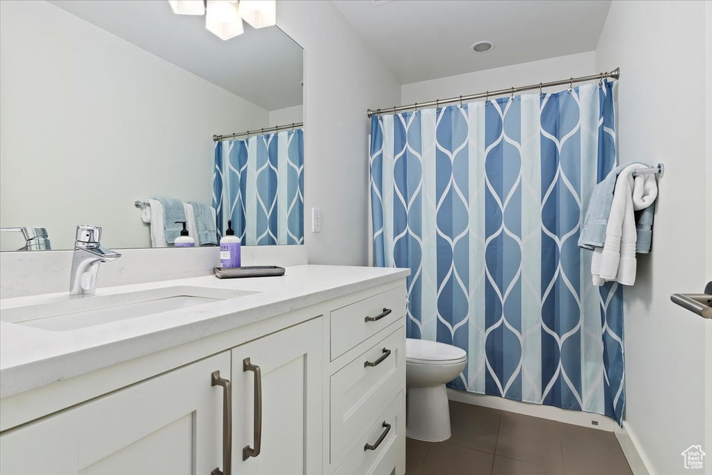 Bathroom featuring vanity, tile patterned flooring, toilet, a shower with shower curtain, and baseboards