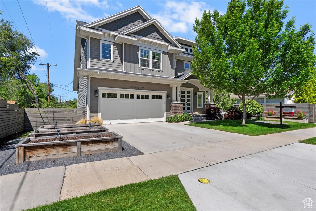 Craftsman-style house featuring board and batten siding, a garden, driveway, and an attached garage