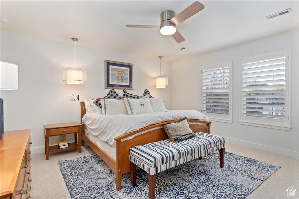 Bedroom with light colored carpet, baseboards, and ceiling fan