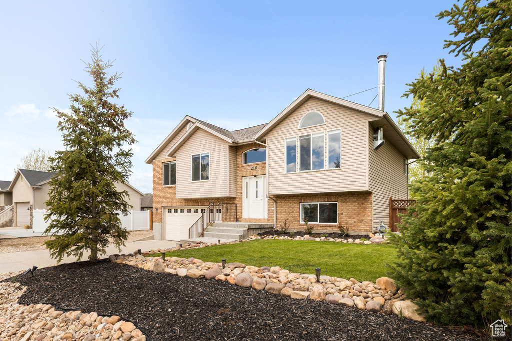 Split foyer home featuring concrete driveway, brick siding, and a garage