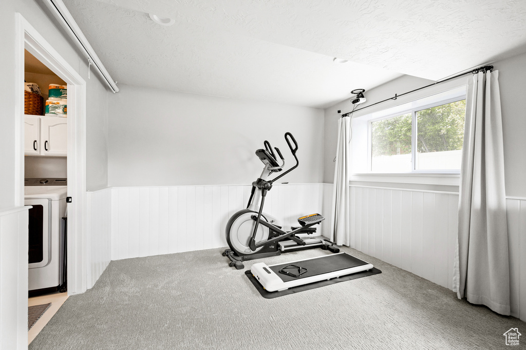 Workout area with washer / dryer, a wainscoted wall, carpet flooring, and a textured ceiling