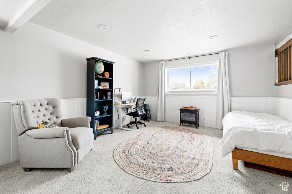 Carpeted bedroom featuring wainscoting, an office area, and a textured ceiling