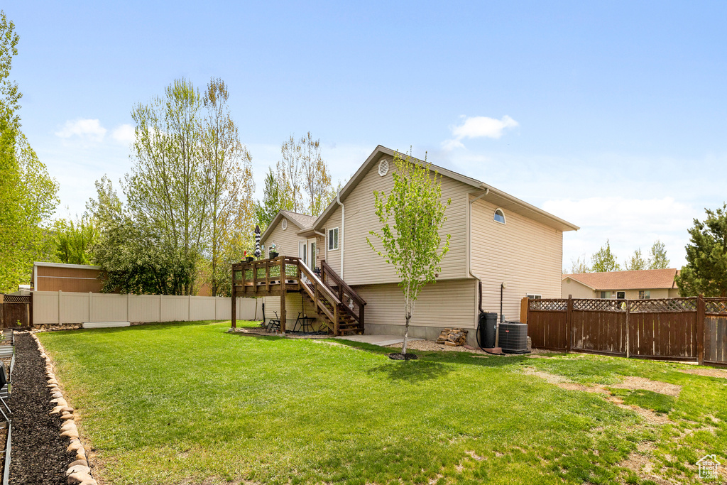 View of yard with stairs, a wooden deck, and central AC unit