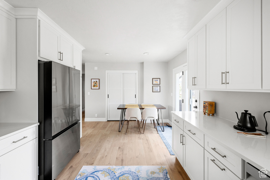 Kitchen with freestanding refrigerator, light countertops, and light wood-style floors