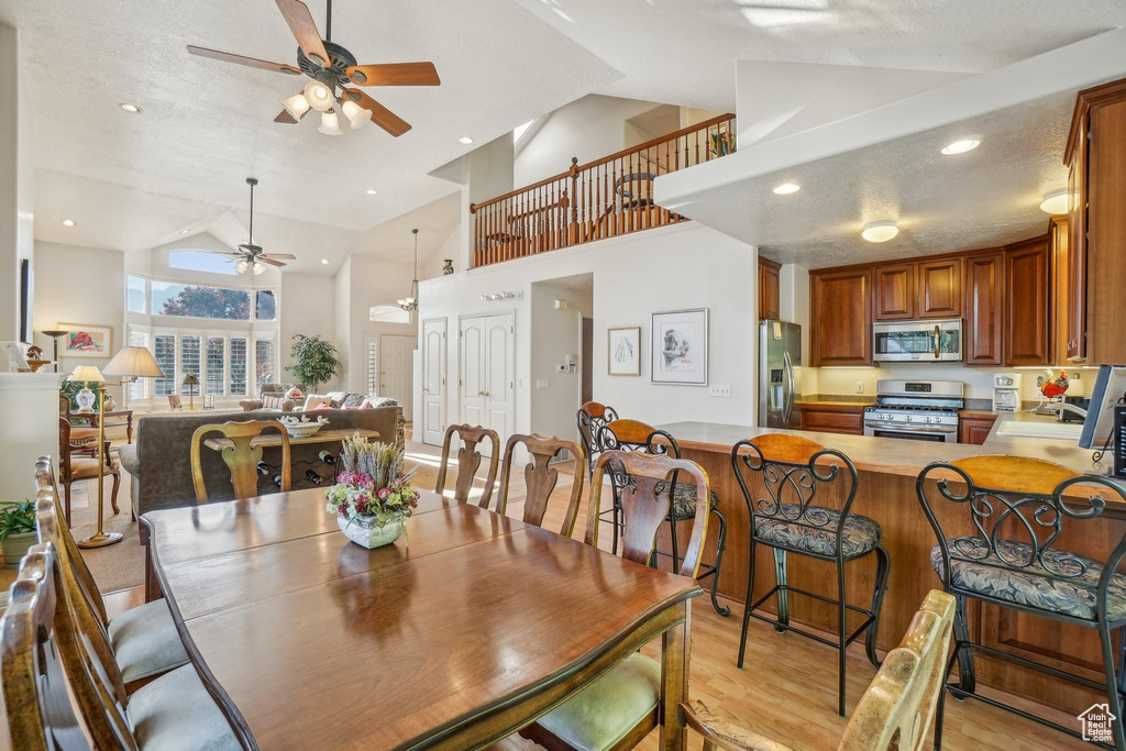 Dining area with ceiling fan, light wood-style flooring, high vaulted ceiling, and recessed lighting