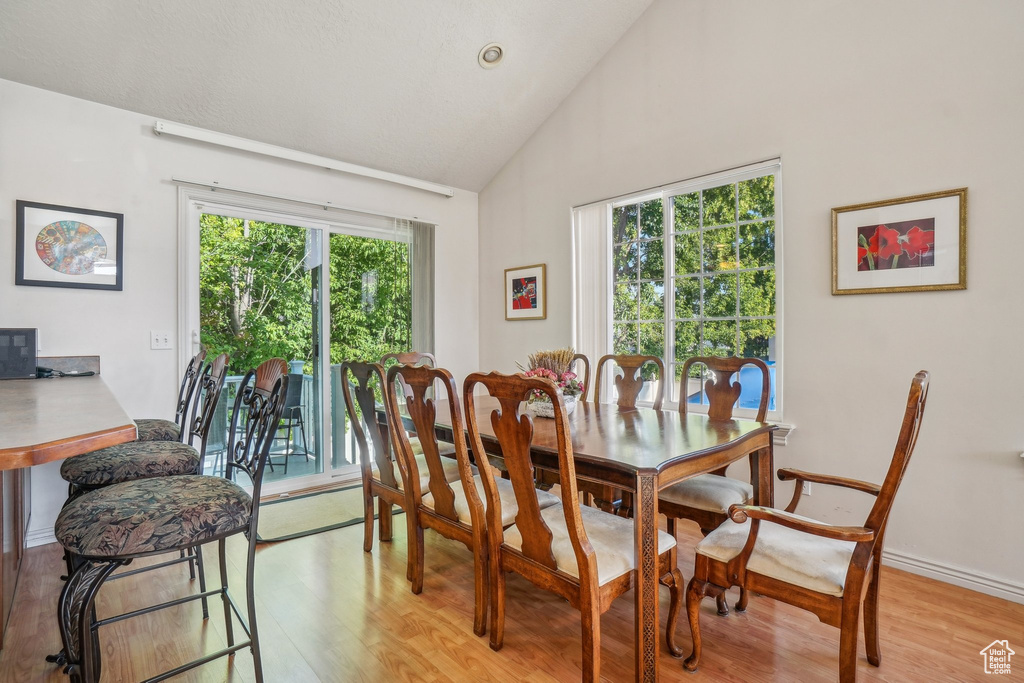Dining space with light wood finished floors and high vaulted ceiling