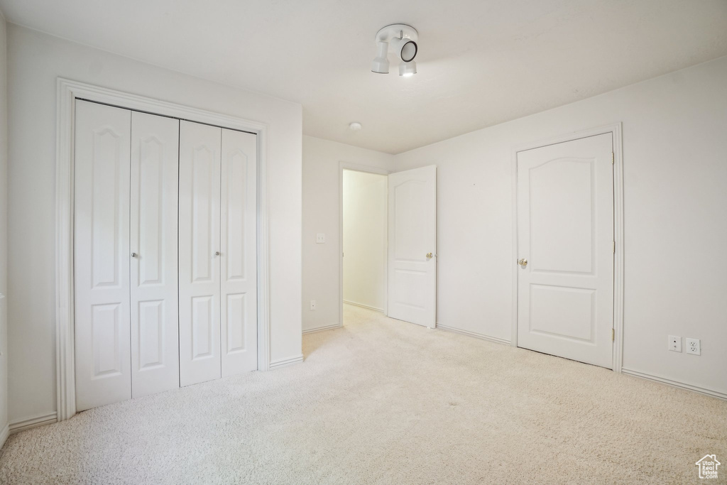 Unfurnished bedroom with carpet flooring, baseboards, and a closet