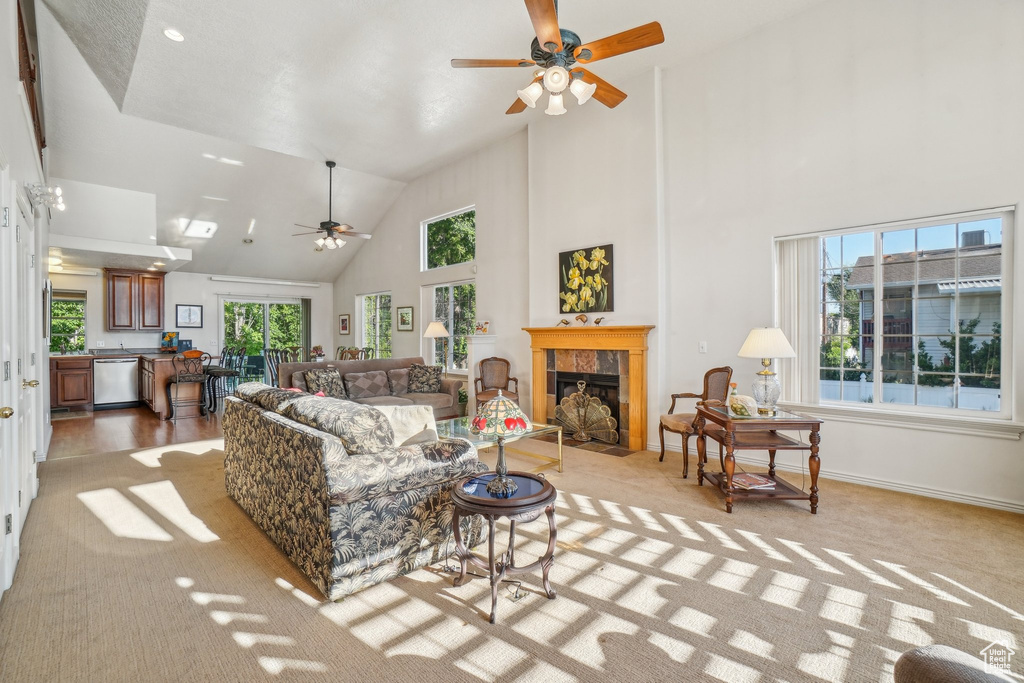 Living area with ceiling fan, high vaulted ceiling, light carpet, a tile fireplace, and baseboards