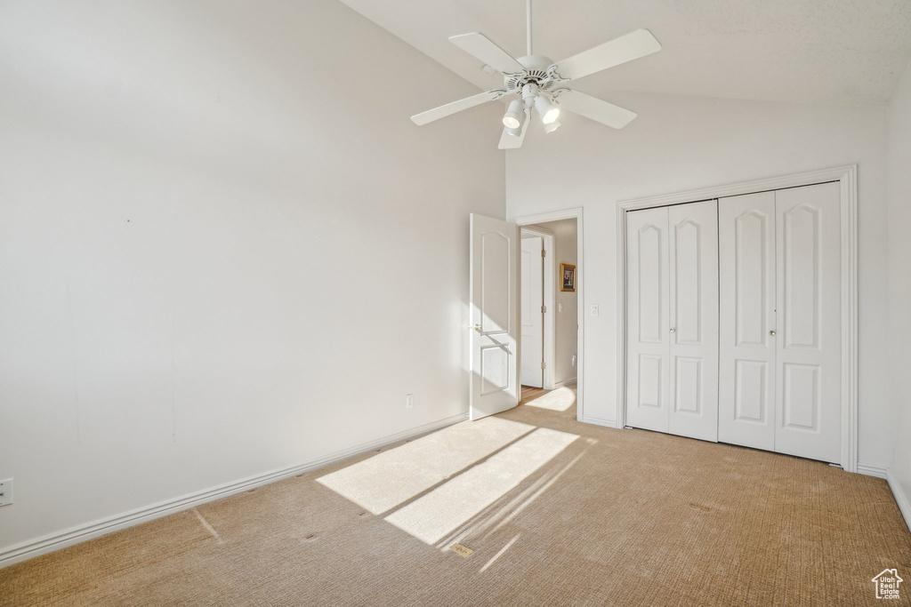 Unfurnished bedroom featuring carpet floors, a closet, high vaulted ceiling, a ceiling fan, and baseboards