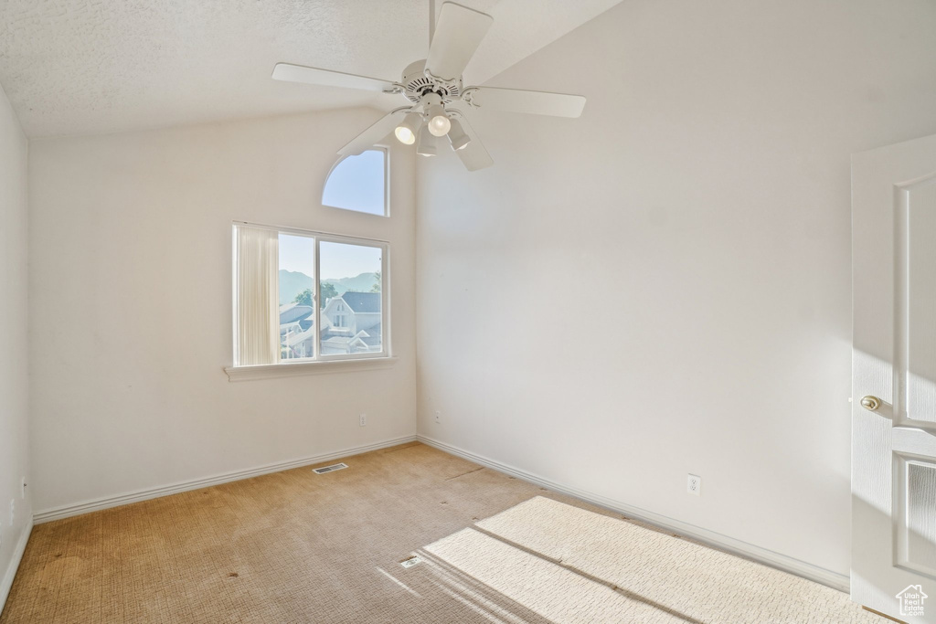 Unfurnished room with light carpet, ceiling fan, lofted ceiling, and baseboards