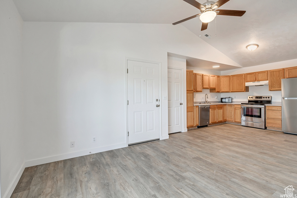 Kitchen featuring stainless steel appliances, a ceiling fan, light countertops, vaulted ceiling, and under cabinet range hood