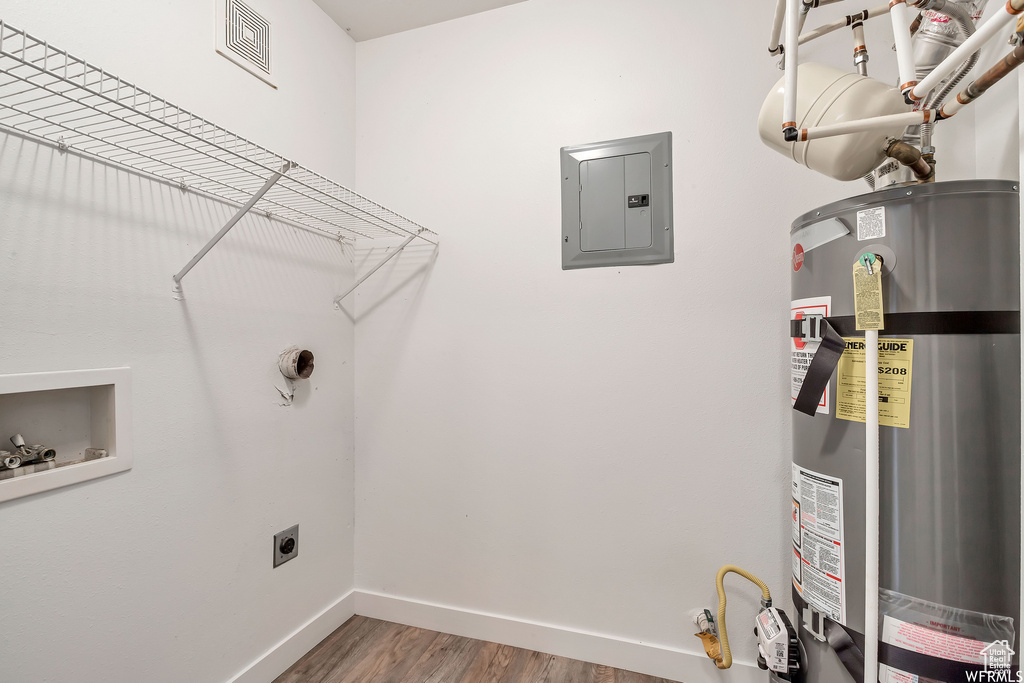 Laundry room featuring gas water heater, electric panel, electric dryer hookup, wood finished floors, and baseboards