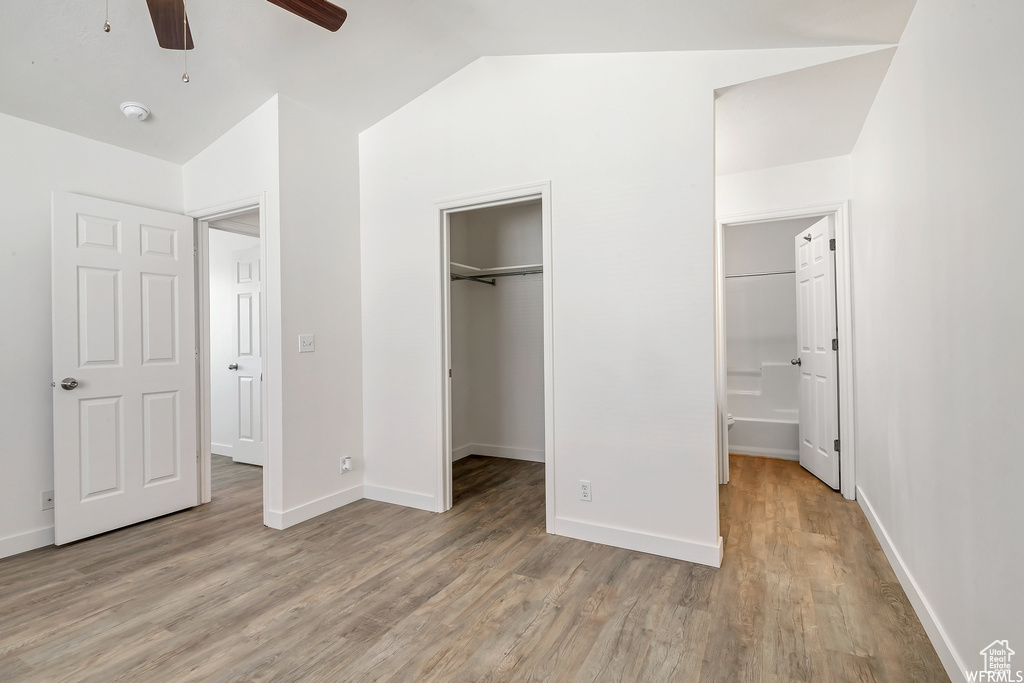 Unfurnished bedroom with light wood-type flooring, vaulted ceiling, baseboards, a closet, and a spacious closet